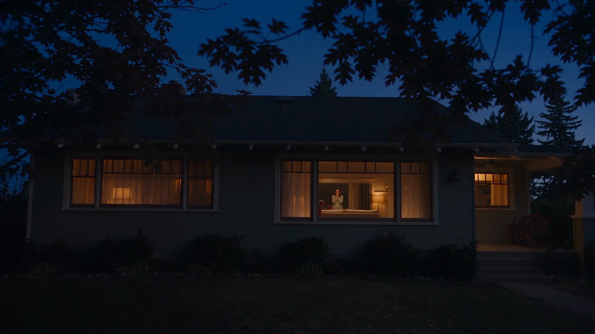 A family in homemade superhero capes playing together in the warmly lit living room of their home at dusk